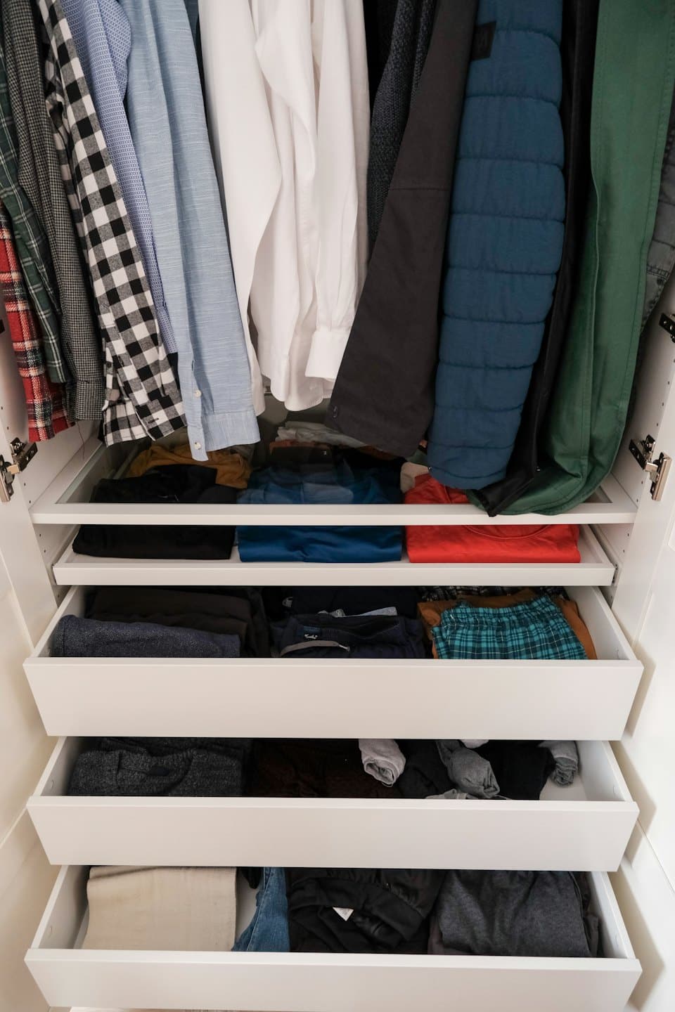 Open modern wardrobe with neatly organized men's clothes.