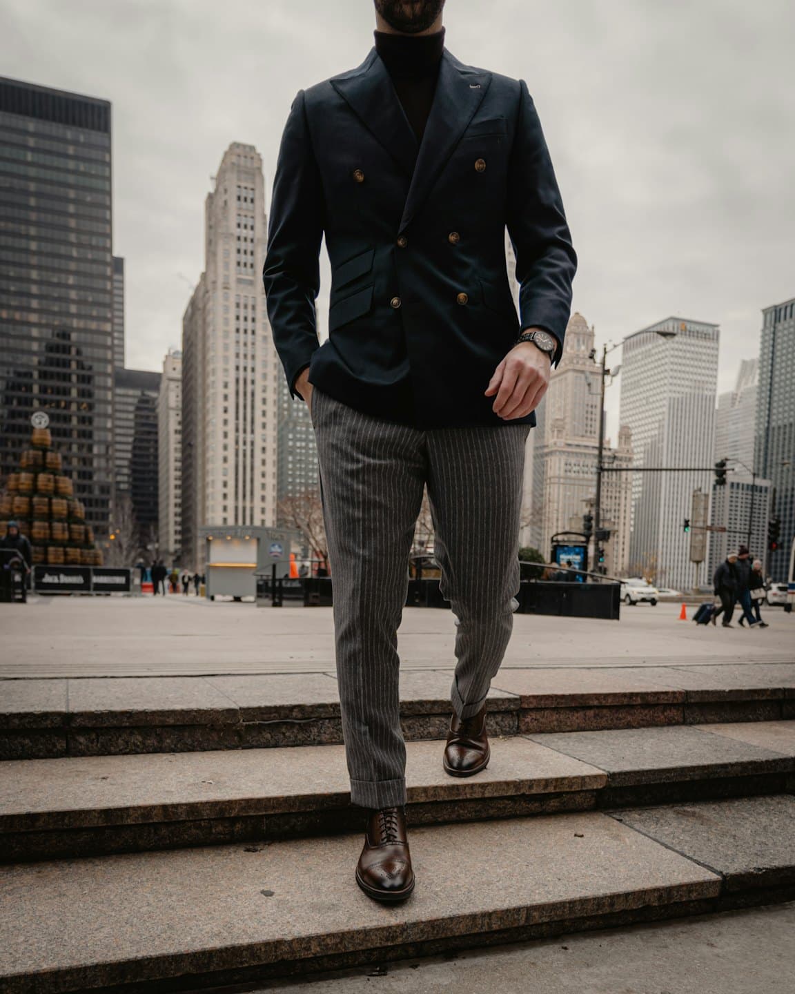 Man in navy blazer walks down granite steps outside.